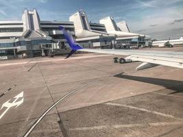 luchthaven met Internationale vluchten. een reusachtig gebouw met landingsbanen in de venster. dichtbij passagiers in de venster kan zien de staart van de vlak foto