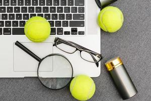 top visie van laptop, sport- apparatuur, tennis bal, shuttle, bril aon de sport- toediening grijs table.business concept. foto