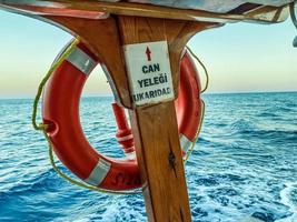 een oranje reddingsboei gehecht naar de dek van de schip. rubber beschermend uitrusting in geval van menselijk overstromingen. zwemmen onderwater- in de zee foto