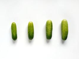 vier komkommers van klein naar groot in een rij in wit achtergrond foto