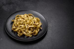 heerlijk vers pasta met pesto saus en zeevruchten Aan een zwart bord foto