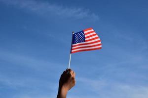 Amerikaans nationaal vlag Holding in hand- tegen blauwe lucht, zacht en selectief focus. foto