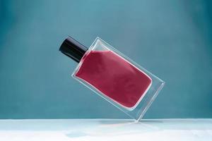 geschorst magenta glas parfum fles Aan blauw achtergrond foto