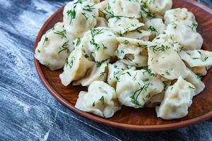 traditioneel Russisch pelmeni of ravioli, knoedels met vlees Aan hout zwart achtergrond. Russisch voedsel en Russisch keuken concept. foto