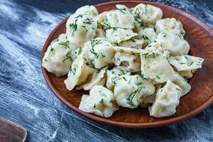 traditioneel Russisch pelmeni of ravioli, knoedels met vlees Aan hout zwart achtergrond. Russisch voedsel en Russisch keuken concept. foto