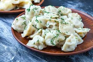 traditioneel Russisch pelmeni of ravioli, knoedels met vlees Aan hout zwart achtergrond. Russisch voedsel en Russisch keuken concept. foto