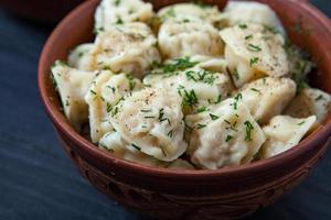 traditioneel Russisch pelmeni of ravioli, knoedels met vlees Aan hout zwart achtergrond. Russisch voedsel en Russisch keuken concept. foto