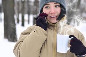 winter portret van jong meisje met smartphone en koffie kop foto