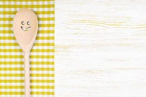 keukenmodel. houten lepel met glimlach op witte houten achtergrond. voedsel achtergrond met kopie ruimte foto