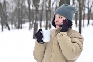 winter portret van jong meisje met smartphone en koffie kop foto