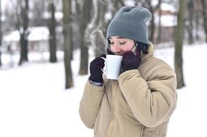 winter portret van jong meisje met smartphone en koffie kop foto