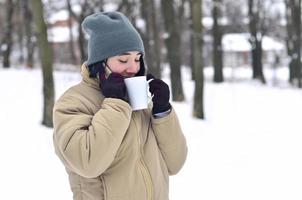 winter portret van jong meisje met smartphone en koffie kop foto