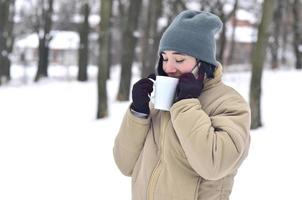 winter portret van jong meisje met smartphone en koffie kop foto