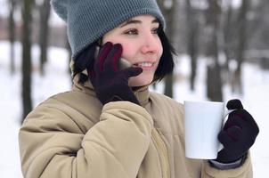 winter portret van jong meisje met smartphone en koffie kop foto