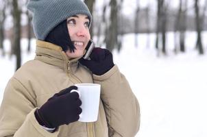 winter portret van jong meisje met smartphone en koffie kop foto