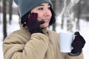 winter portret van jong meisje met smartphone en koffie kop foto