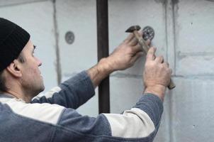 een ouderen werkman klompen een deuvel in een plastic paraplu monteren in een piepschuim muur. de werkwijze van vaststelling uitgebreid polystyreen platen. opwarming van de facade van de gebouw foto