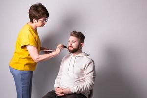 gebaard Mens krijgen verzinnen. vrouw visagist werken met borstel. copyspace foto