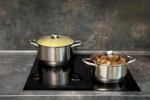 potten met schnitzels en gekookt aardappelen Aan de inductie fornuis foto