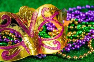carnaval masker en kleurrijk kralen Aan groen glimmend achtergrond. mardi gras concept. dik dinsdag symbool. foto