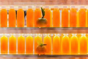 vers oranje sap in flessen in koelkast plank. foto
