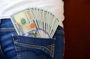 een groot aantal van dollar rekeningen leugens in de terug zak- van de meisjes jeans foto