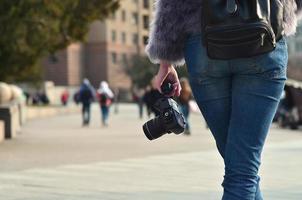 achterzijde visie van een meisje met een digitaal camera Aan een druk straat ba foto