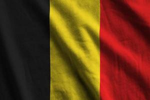 belgie vlag met groot vouwen golvend dichtbij omhoog onder de studio licht binnenshuis. de officieel symbolen en kleuren in banier foto
