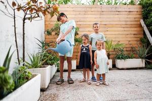 kinderen met kan gieter de bloemen Aan de terras van de huis. foto