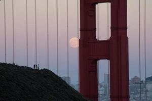 volle maan door kabels van gouden poort brug foto
