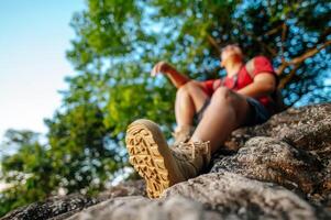 jong backpacker Mens zittend Aan rotsachtig kliffen met rugzak foto