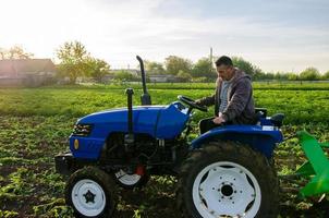 de boer werken in de veld- met een tractor. oogsten aardappelen. oogst eerste aardappelen in vroeg de lente. landbouw en landbouwgrond. agro industrie en landbouwbedrijf. ondersteuning voor boerderijen foto