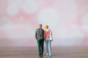 miniatuur mensen Mens en vrouw in gewoontjes kleding staand samen Aan roze achtergrond foto
