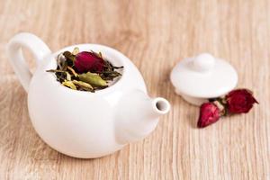 groen thee met fruit, kruiden, roos bloemblaadjes in een theepot foto