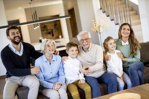 multi generatie familie zittend samen Aan de sofa Bij huis en aan het kijken TV foto