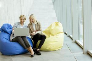 onderneemsters gebruik makend van laptop computer Aan lui Tassen in de modern kantoor foto