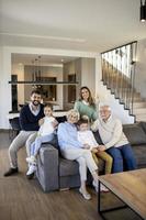 multi generatie familie zittend samen Aan de sofa Bij huis foto