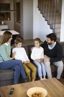 jong familie aan het kijken TV samen Aan de sofa in de leven kamer foto