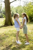 twee kleine meisjes hand in hand in het park foto