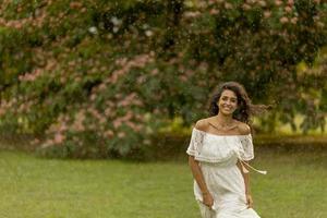 vrolijke jonge vrouw gevangen door de zomerregen in het park foto