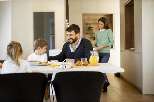 jong moeder voorbereidingen treffen ontbijt voor haar familie in de keuken foto