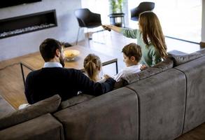 jong familie aan het kijken TV samen Aan de sofa in de leven kamer foto