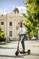jonge Afro-Amerikaanse met behulp van elektrische scooter op een straat foto
