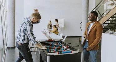 jong gewoontjes multi-etnisch bedrijf mensen spelen tafel Amerikaans voetbal en ontspannende Bij kantoor foto