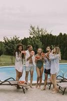 jong mensen staand door de zwemmen zwembad en aan het eten watermellon in de huis achtertuin foto