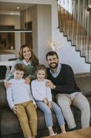 gelukkig familie met twee kinderen genieten tijd samen Aan bankstel in leven kamer foto