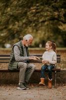 opa spelen rood handen meppen spel met zijn kleindochter in park Aan herfst dag foto