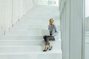 zakenvrouw gebruik makend van mobiel telefoon Aan modern kantoor trap foto