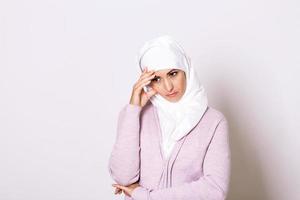 Arabisch saudi emiraten vrouw met hoofd pijn. portret van ongelukkig jong vrouw met slecht hoofdpijn. portret van mooi jong moslim vrouw met kaal schouders aanraken haar tempels gevoel spanning foto