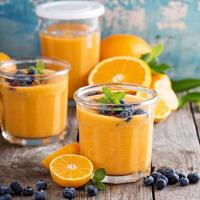 oranje en mango smoothie met muesli en bessen foto